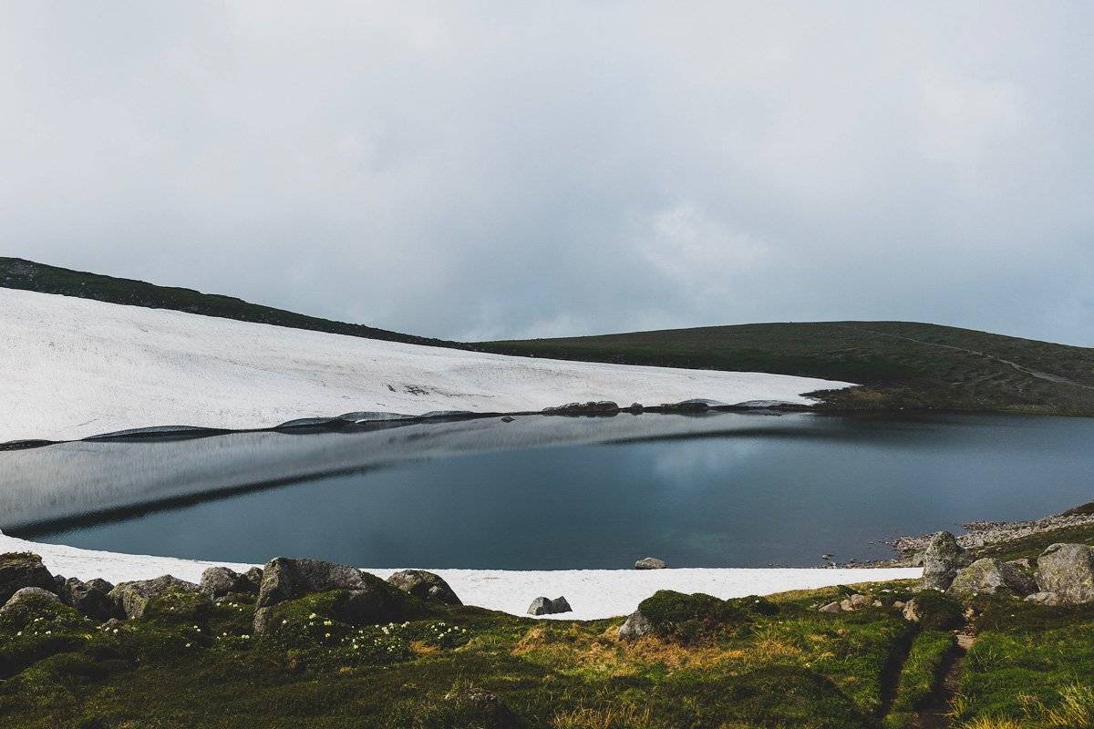 A blue pond surrounded by snow.
