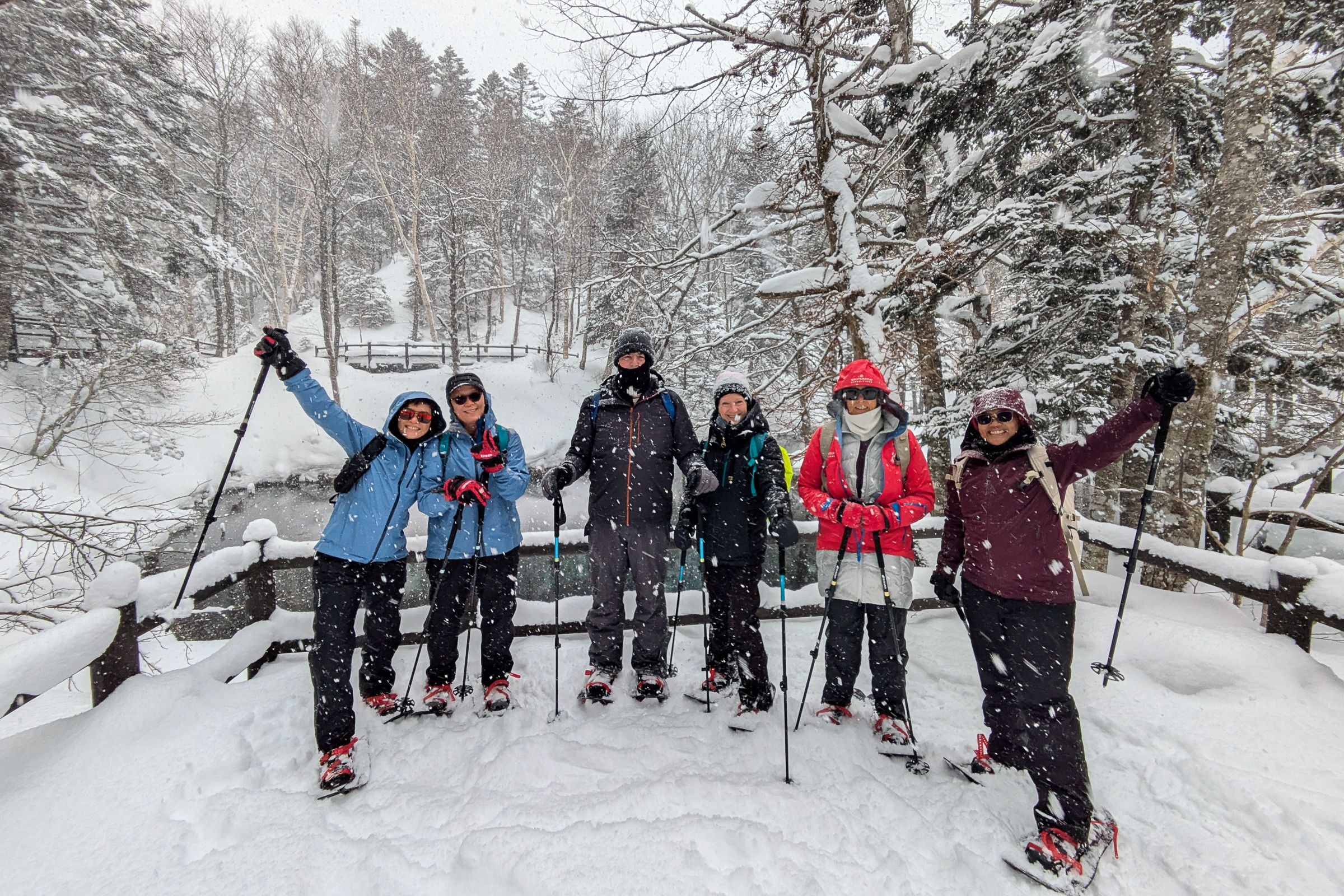 A group of Adventure Hokkaido guests pose for a photo at the snow-surrounded Kaminoko Pond. Despite the falling snow, they look happy and accomplished after their snowshoe trek to this scenic spot.