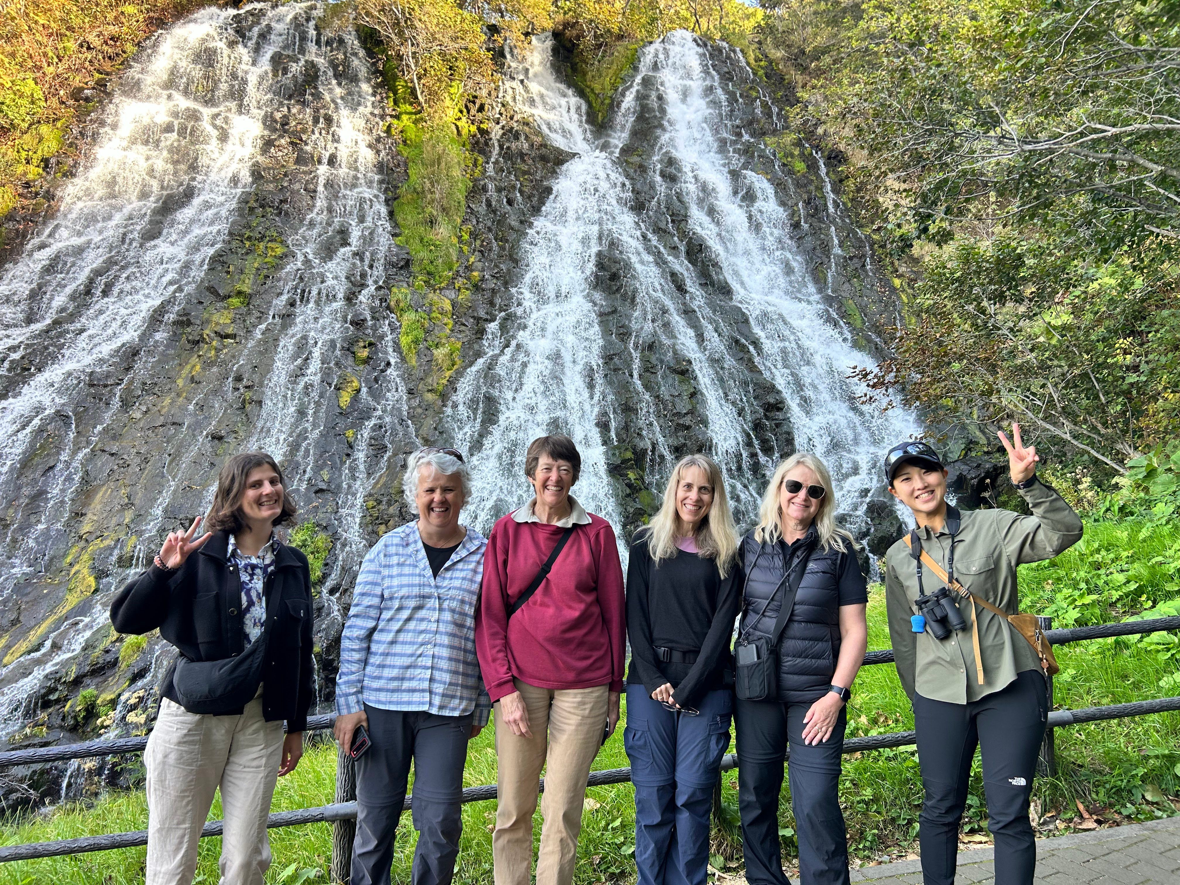 A group of visitors to Hokkaido pose in front of Oshinkoshin Waterfall in the Shiretoko Peninsula.