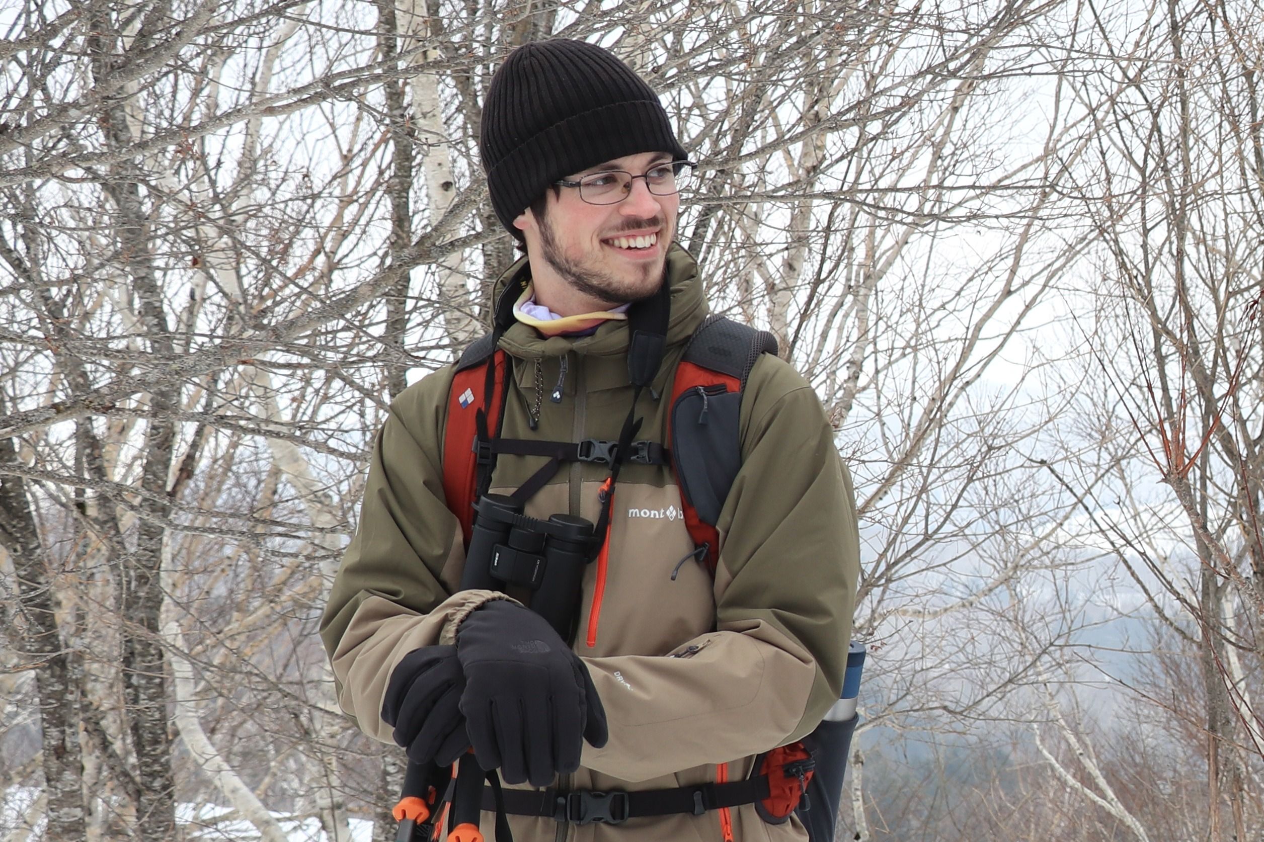 Adventure Hokkaido guide Zac stands in front of birch trees. It's winter and the trees have no leaves.