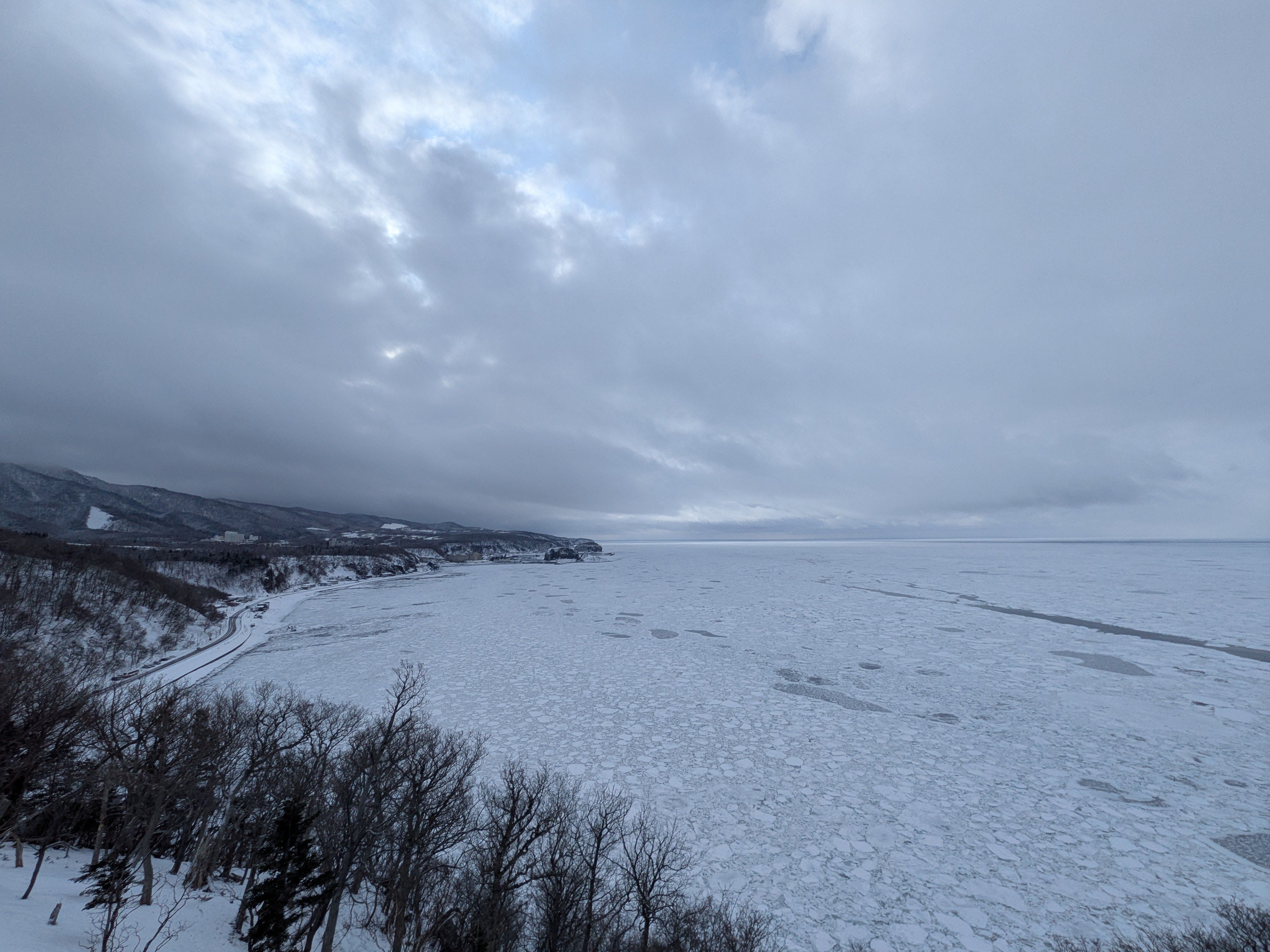 A photograph of a bay on the Shiretoko Peninsula, Hokkaido. The entire bay is covered in drift ice.