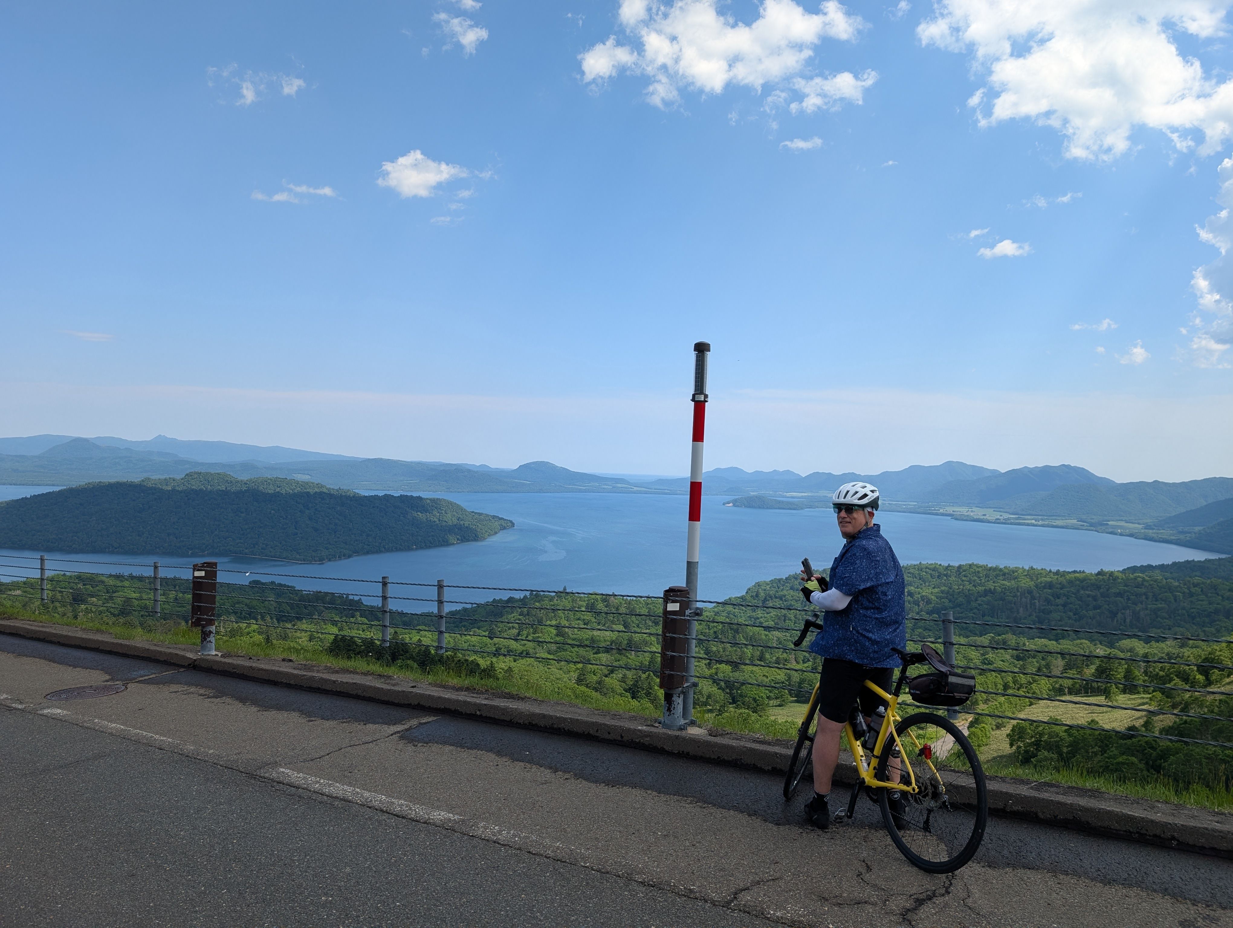A cyclist dismounts his bike on a road overlooking Lake Kussharo in Hokkaido.