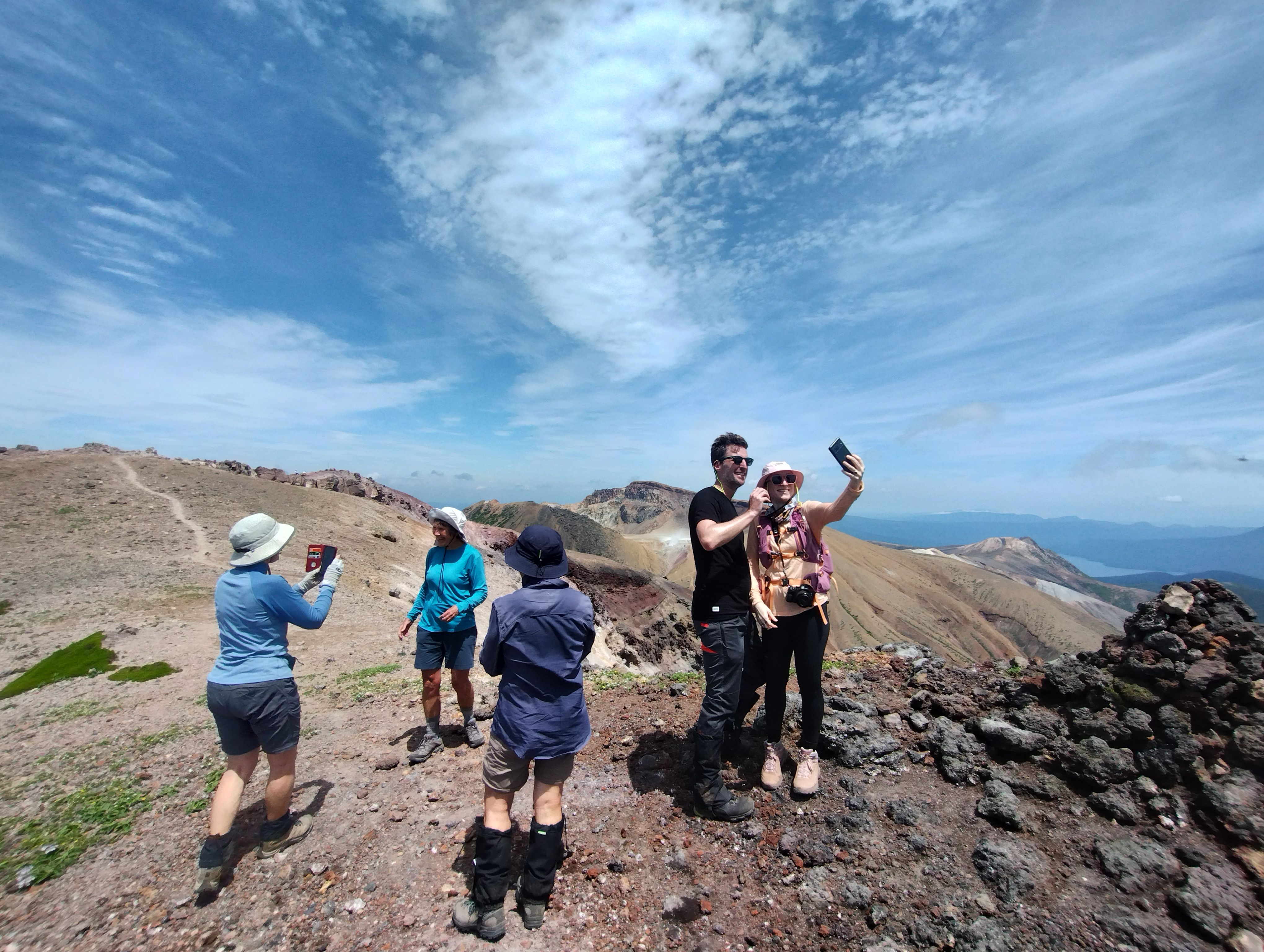 A group of hikers pose with each other to take photographs atop Mt. Meakan. It's a beautiful sunny day.