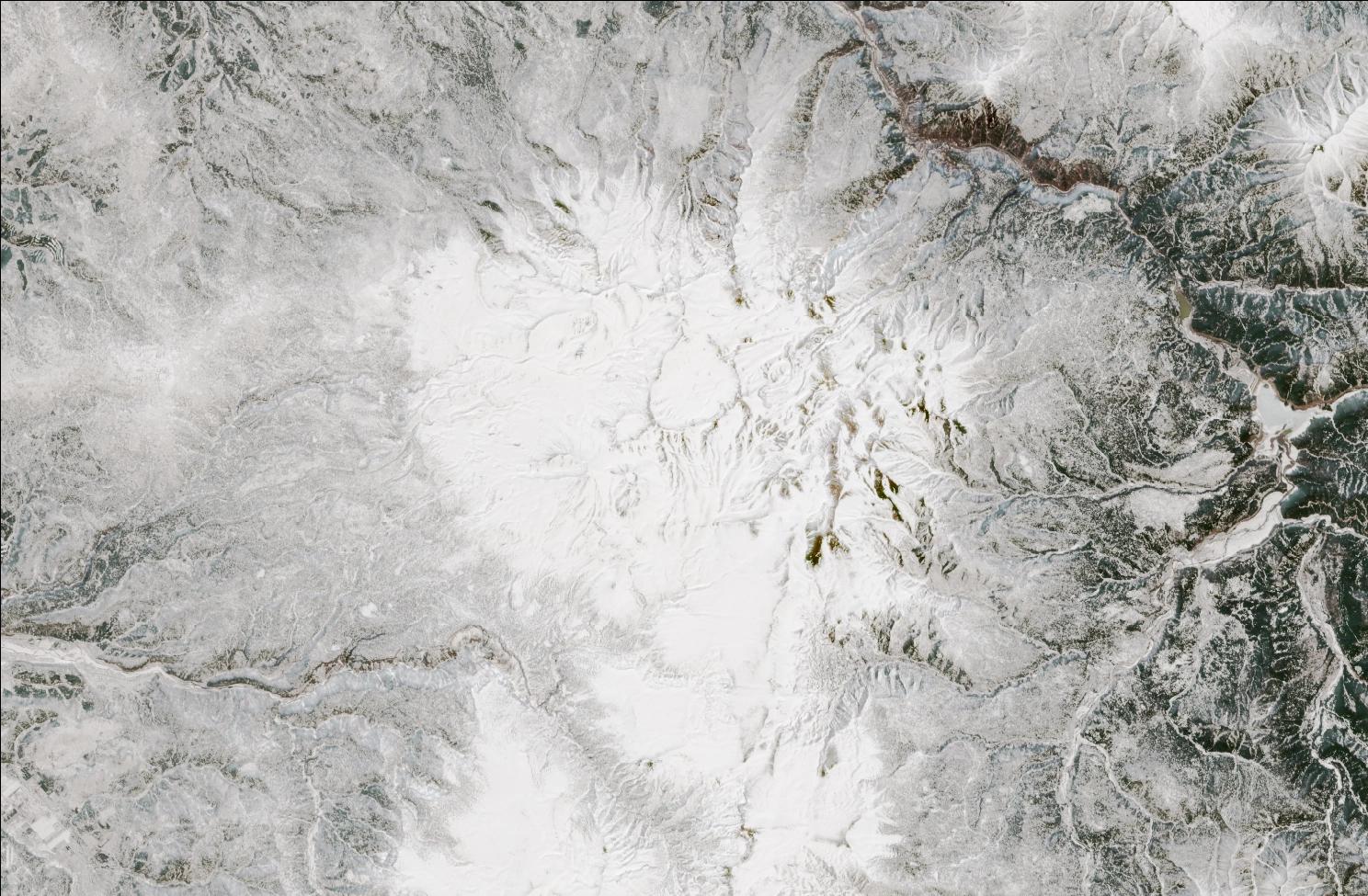A satellite image showing snow over the northern Daisetsuzan mountains. The landscape is mostly white, while exposed ridges and low valleys have no snow.