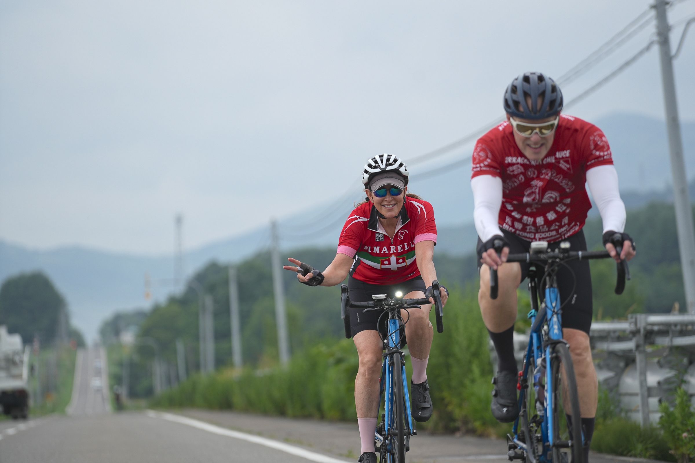 Two cyclists on a straight rural road, Central Hokkaido.