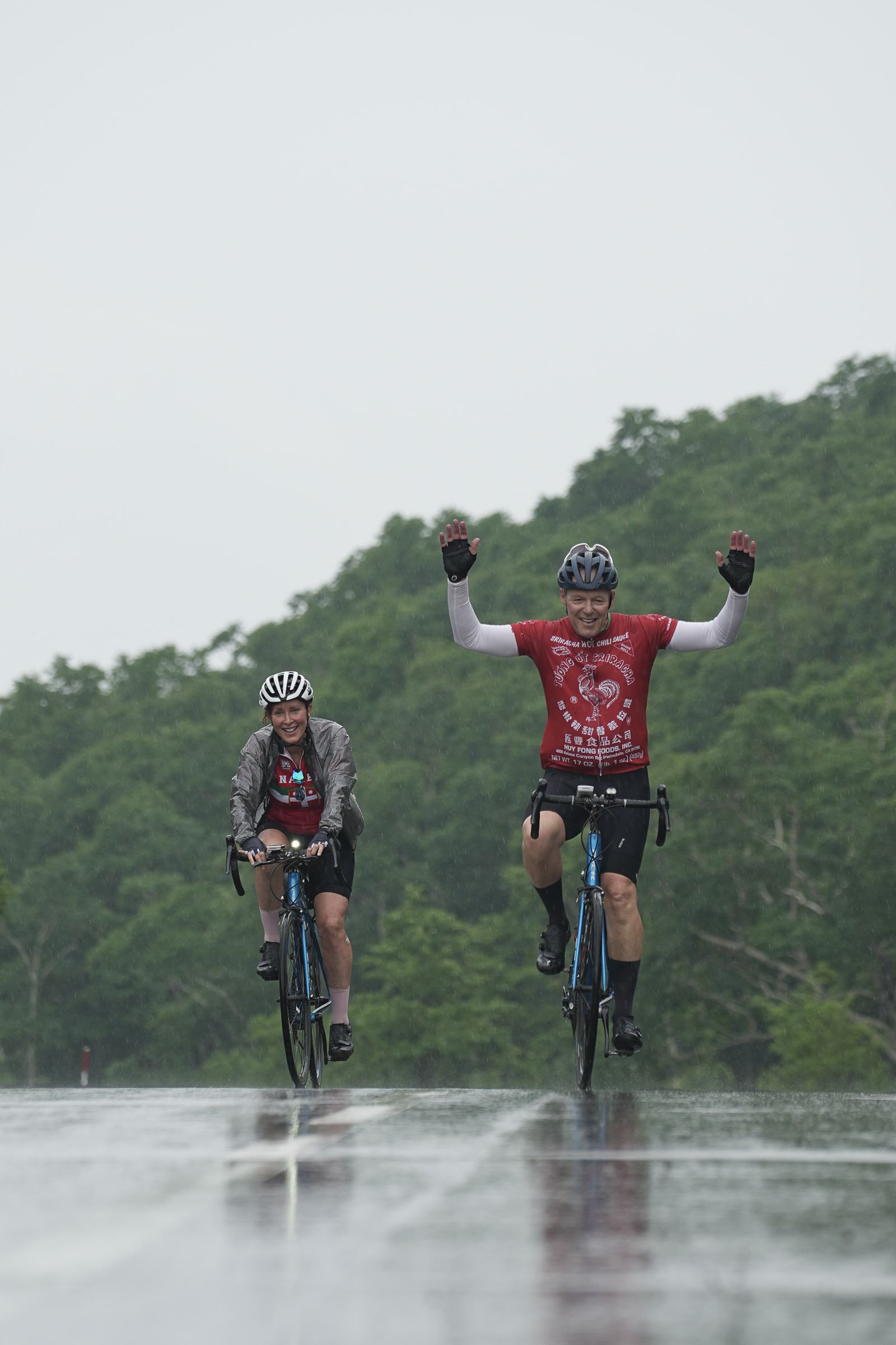 Two cyclists beating the uphill on a rainy summer day.