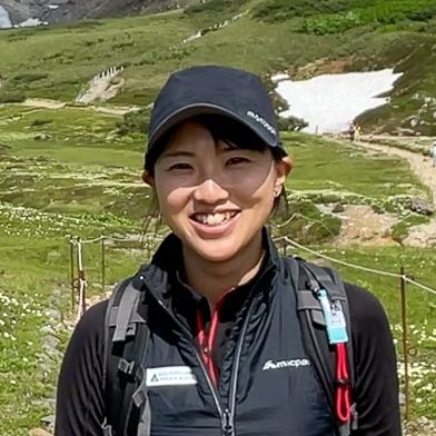 Adventure Hokkaido guide Yuka smiles at the camera while standing in front of Mt Asahidake.