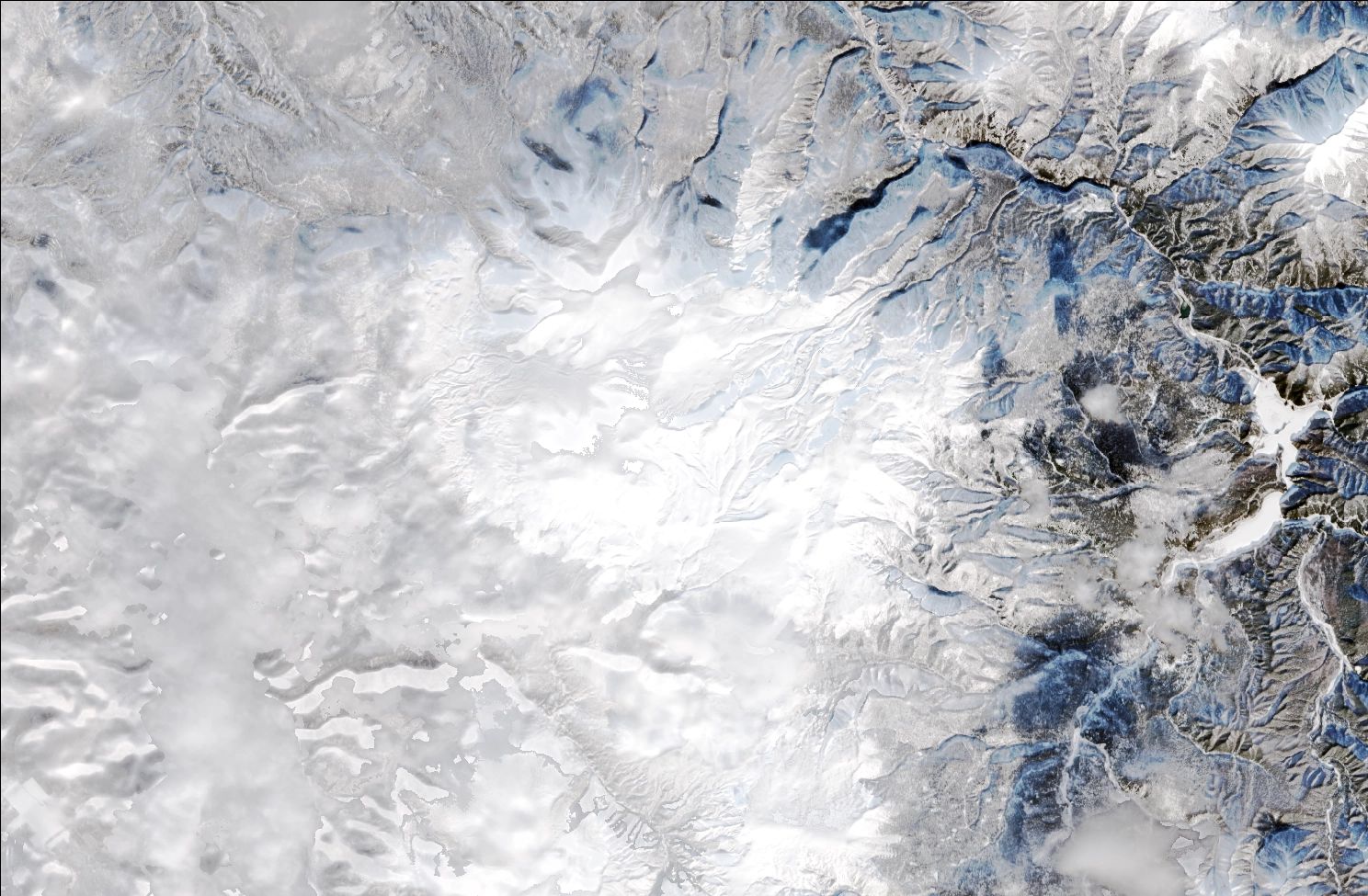A satellite image showing snow over the northern Daisetsuzan mountains. Cloud obscures much of the image, but snow can be seen on the mountains while the valleys remain dark and mostly snow free.