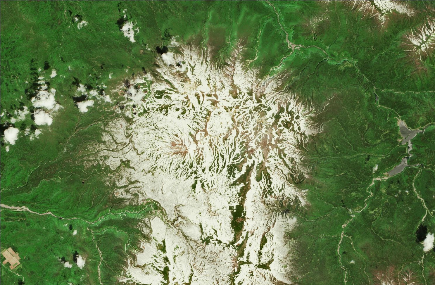 A satellite image showing snow over the northern Daisetsuzan mountains. Strips of snow remain in the mountains while the rest of the landscape is green.