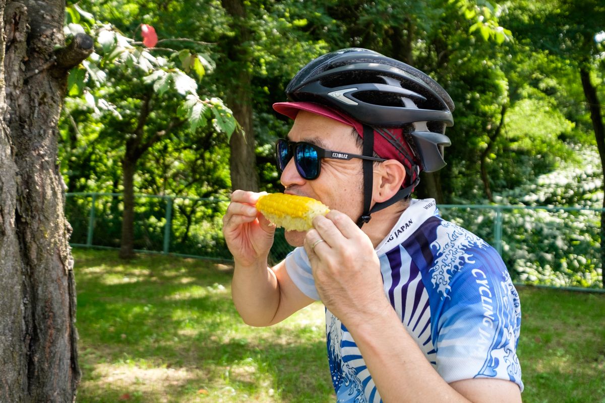 A cycling guide eats sweetcorn from the kob