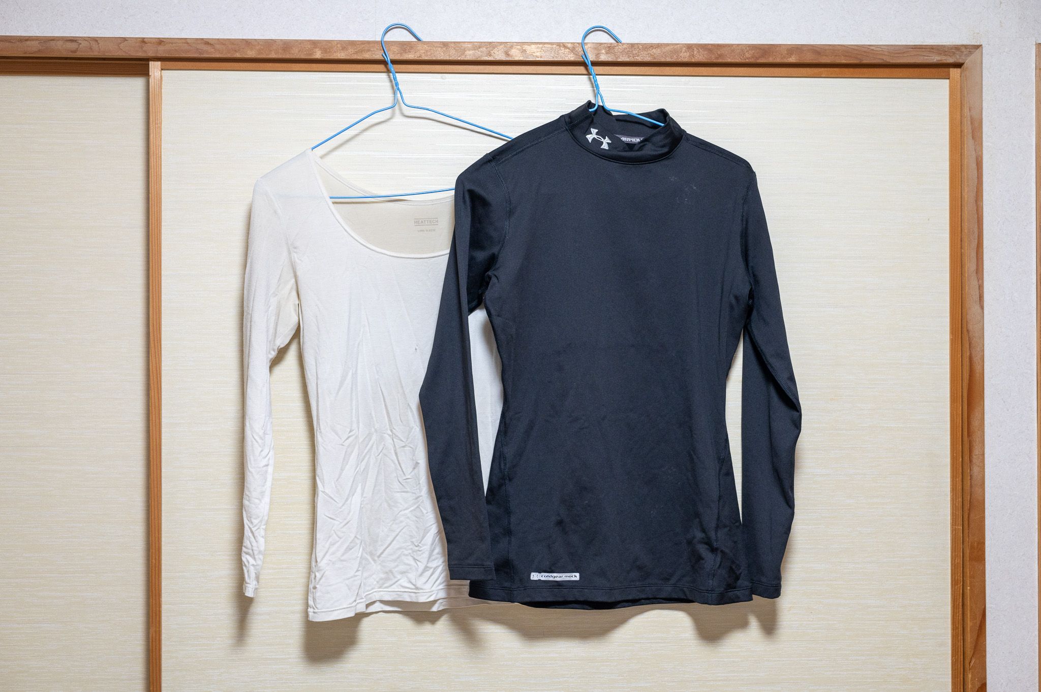 Two thermal tops on hangers against a closet. One is high-necked, the other is a scoop-neck.