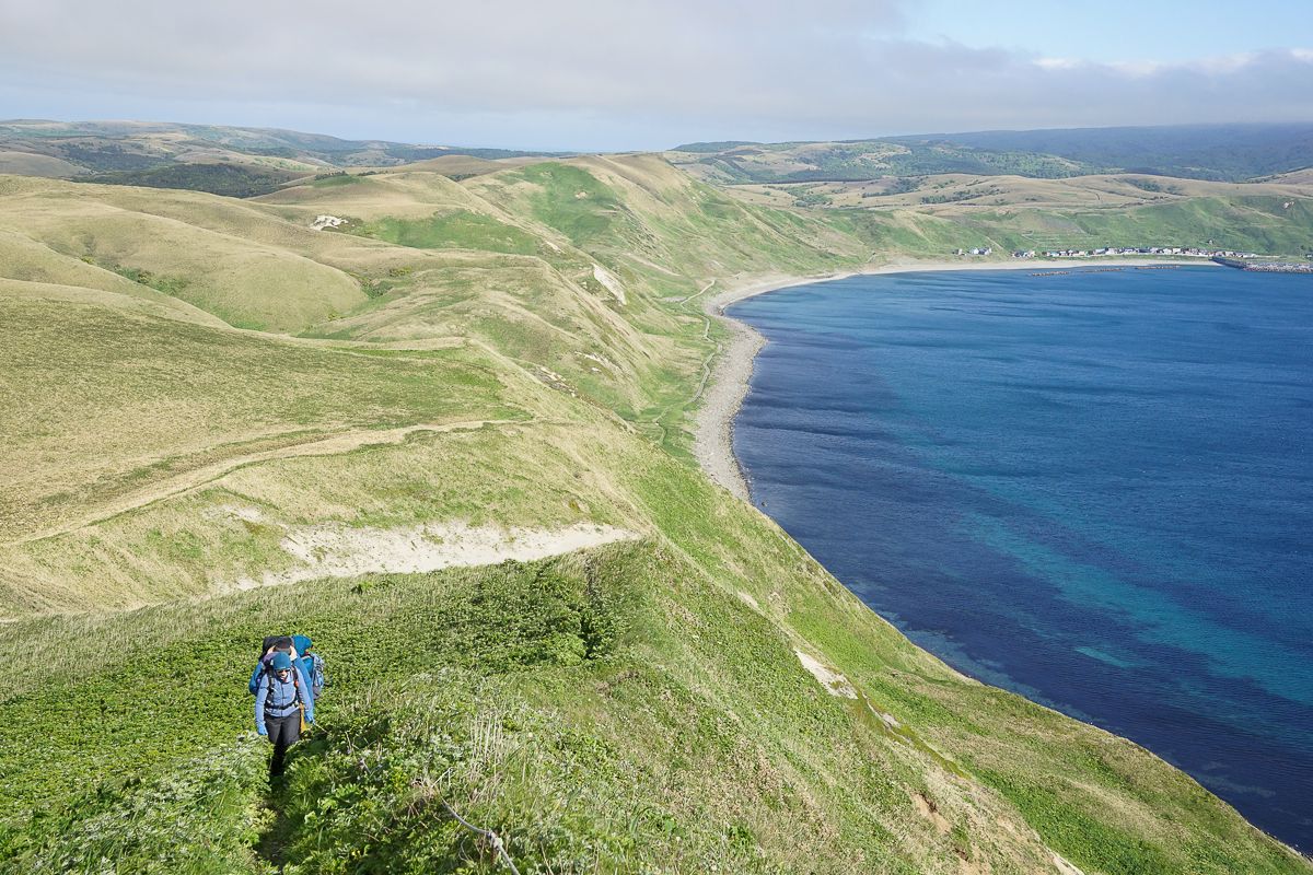 A lone hiker walks along the cliffs on the Misaki Meguri Trail on Rebun island. The sea is a brilliant combination of different shades of blue.