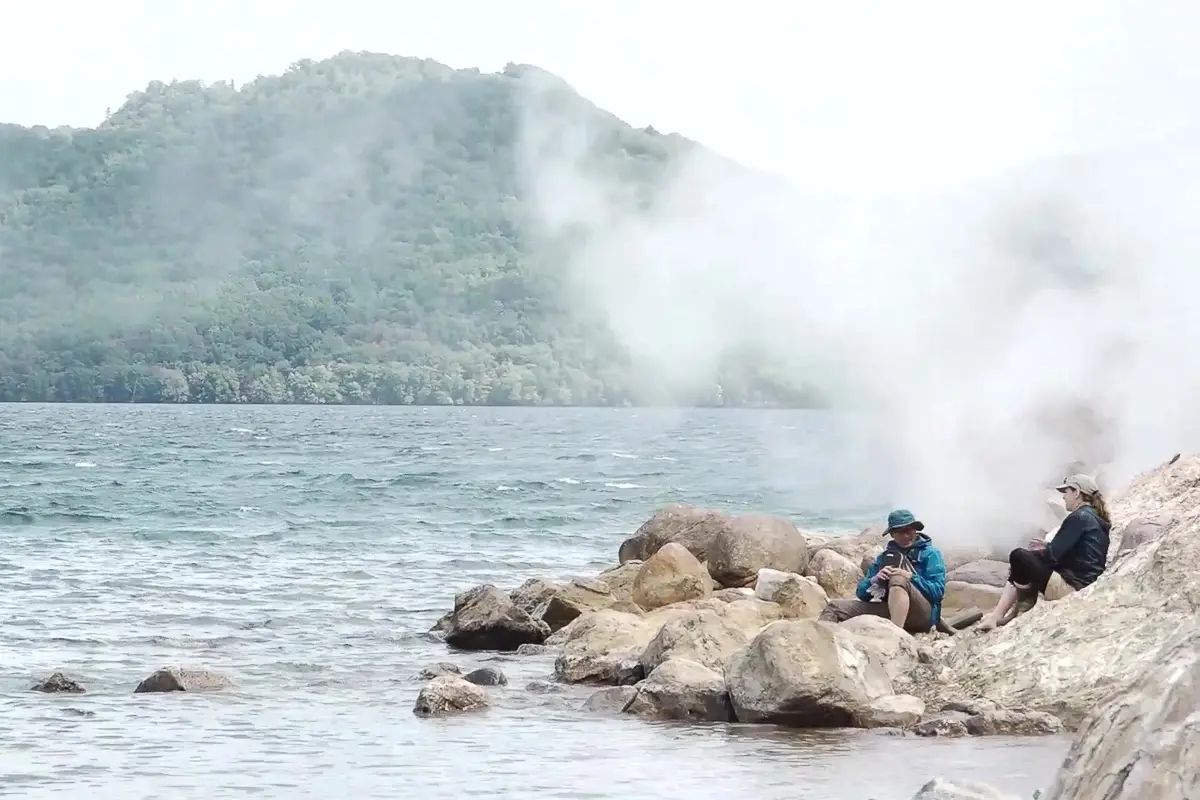 Travellers warming their feet in the hot pools at Lake Kussharo in Hokkaido