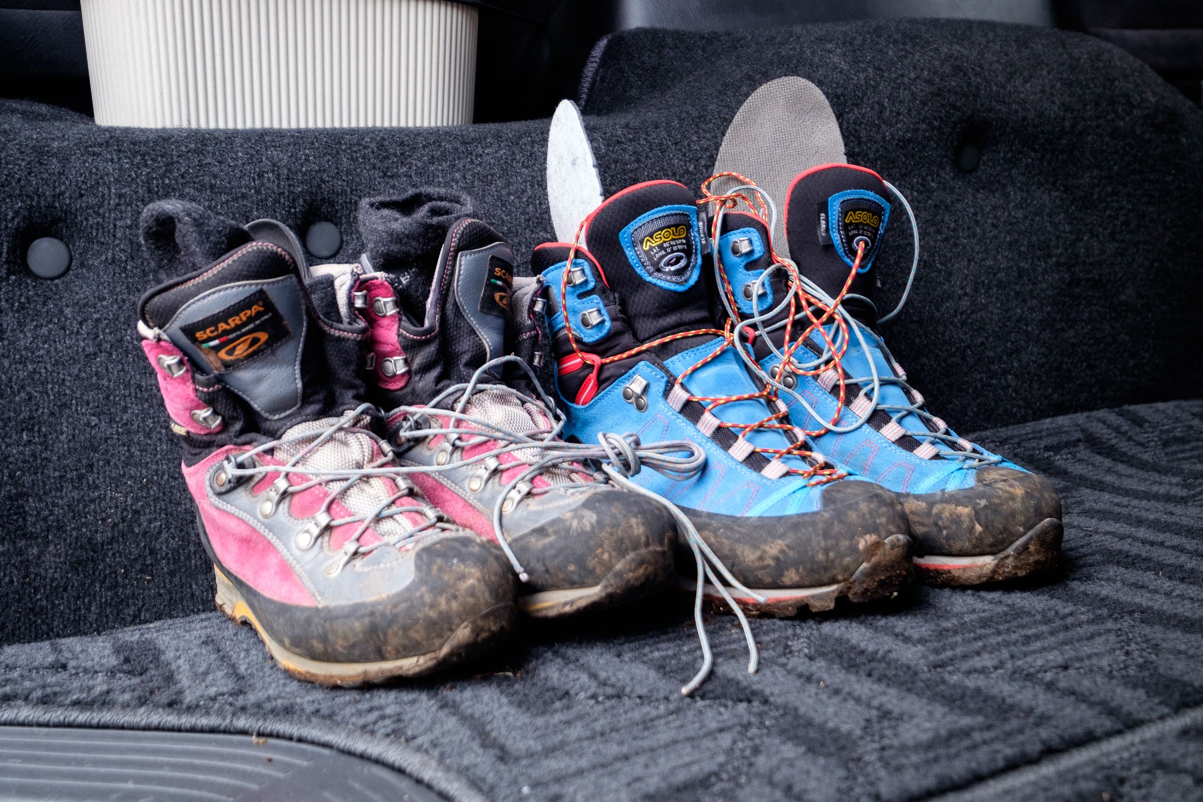 Two pairs of hiking boots sit muddy in a van after a day hiking in the Daisetsuzan National Park