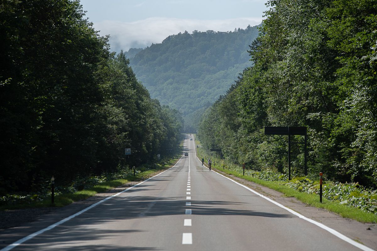 Two cyclists seen in the distance on a long straight road