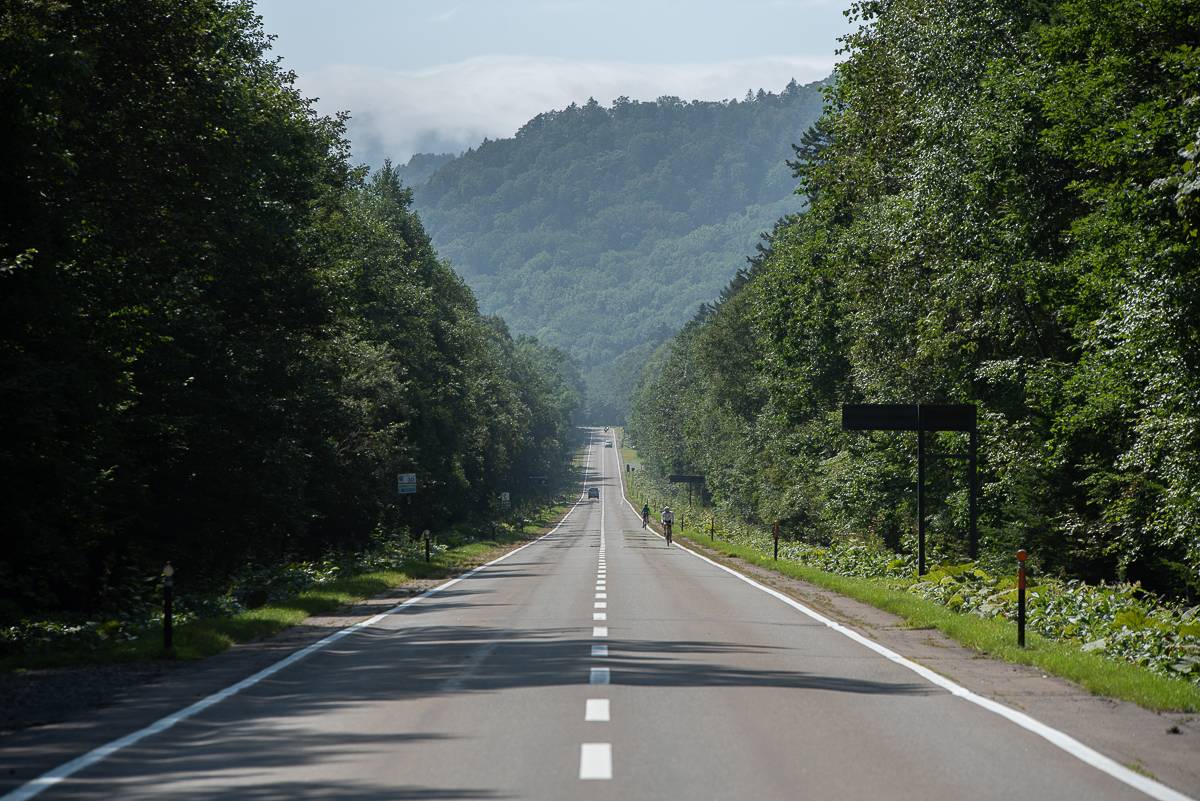 Two cyclists seen in the distance on a long straight road