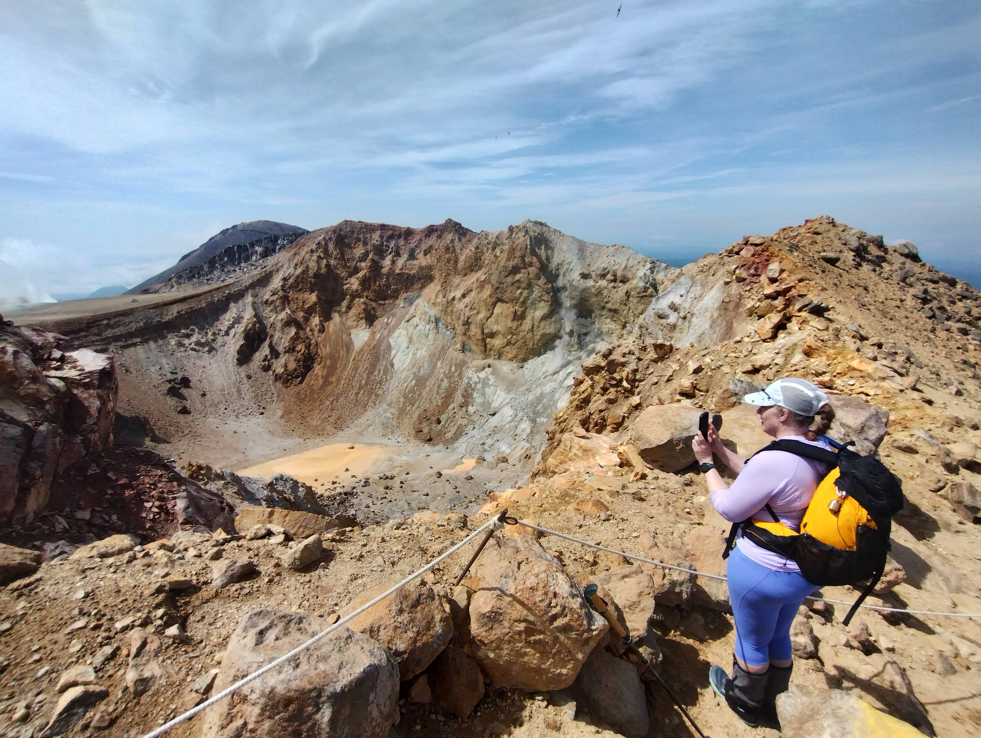 A woman takes a photo on her smartphone of the interior of a volcanic crater on Mt. Meakan, Hokkaido.