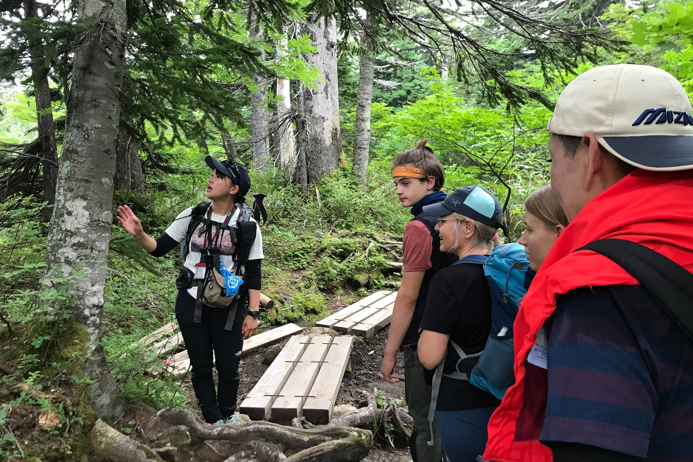 Adventure Hokkaido Guide Yuka stops on a board walk to point out a tree to four guests.