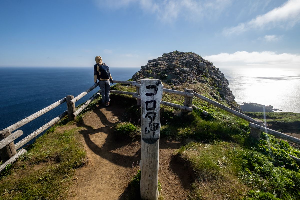 A lone hiker surveys the sea at Cape Gorota's lookout point.