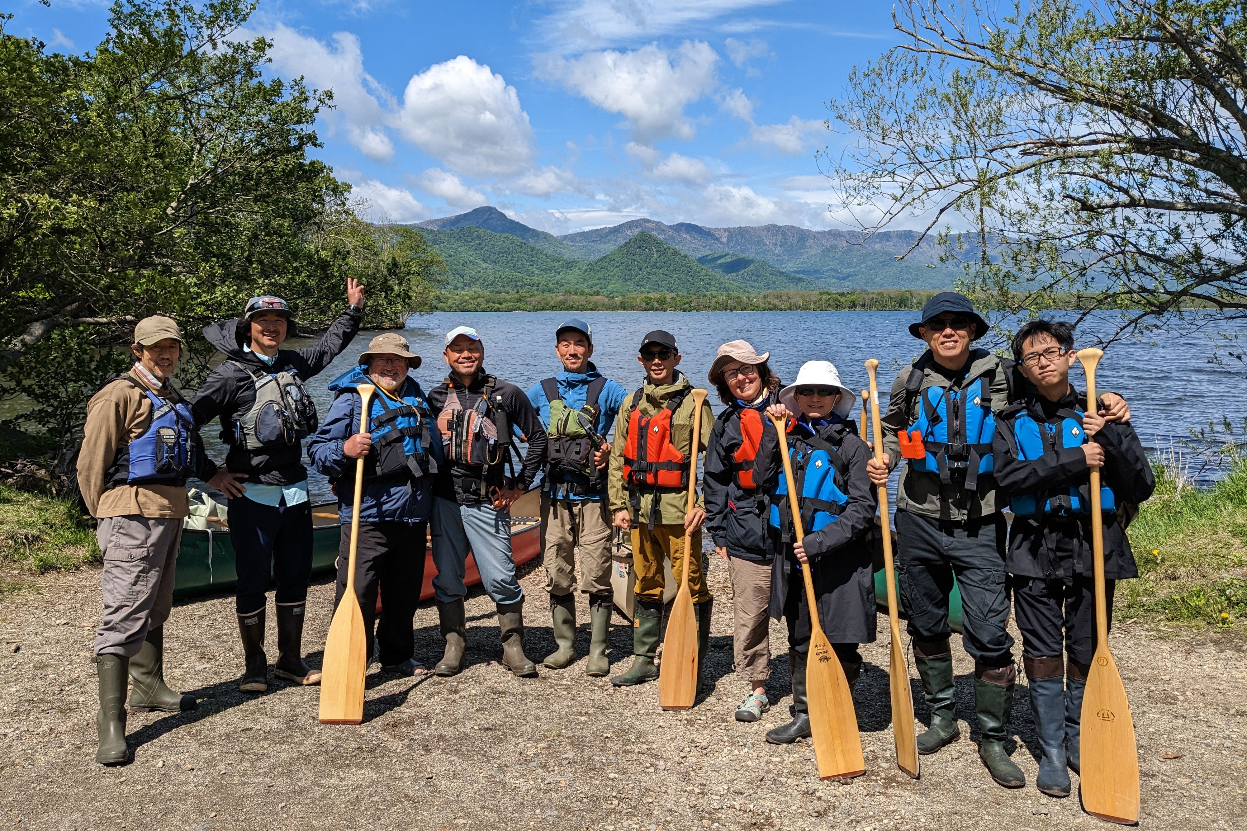 A group of canoeists post with their paddles on the shore of Lake Kussharo in the Akan–Mashu national park