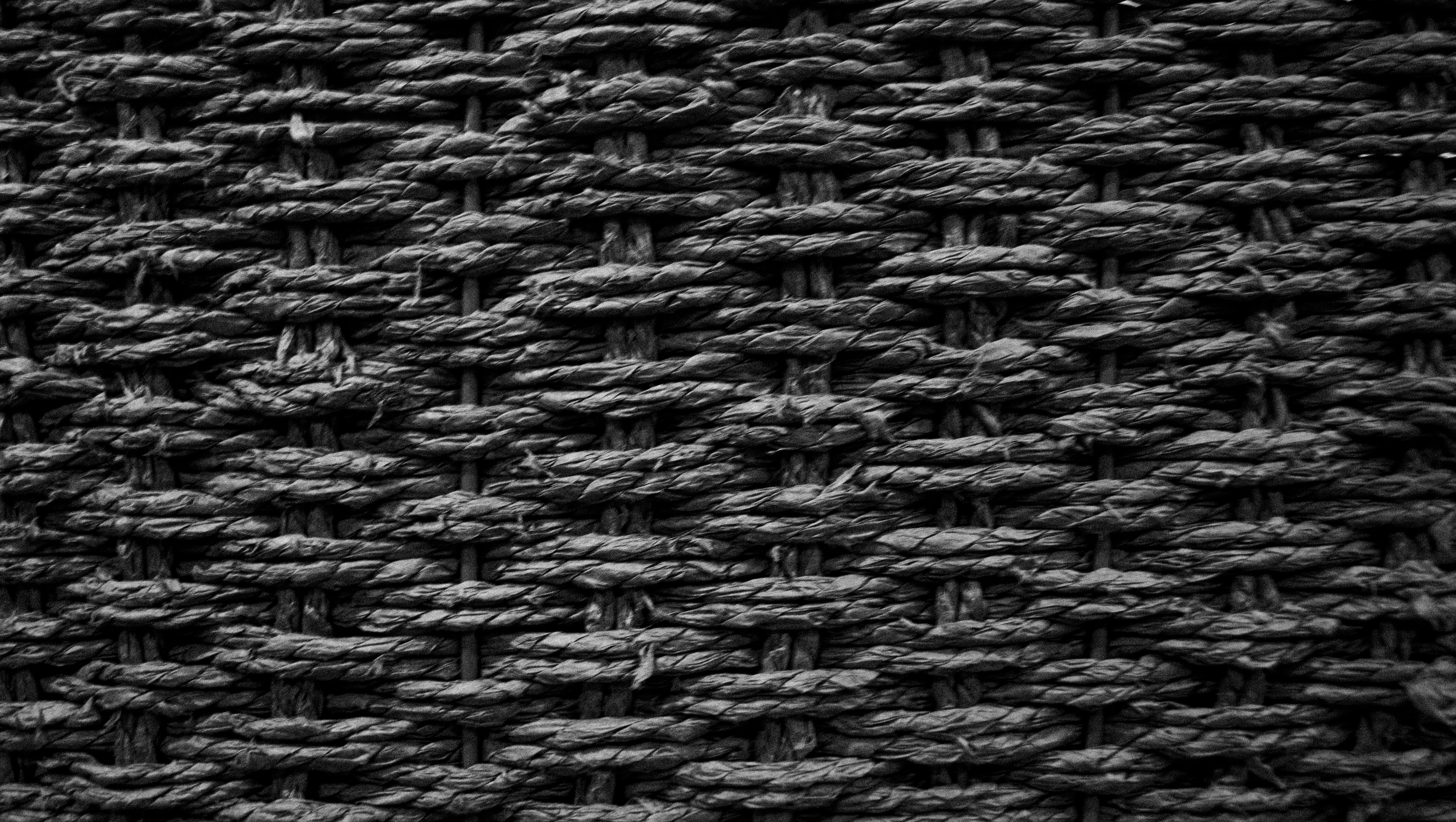 Tight diamond weave of dark woven rattan, grayscale texture