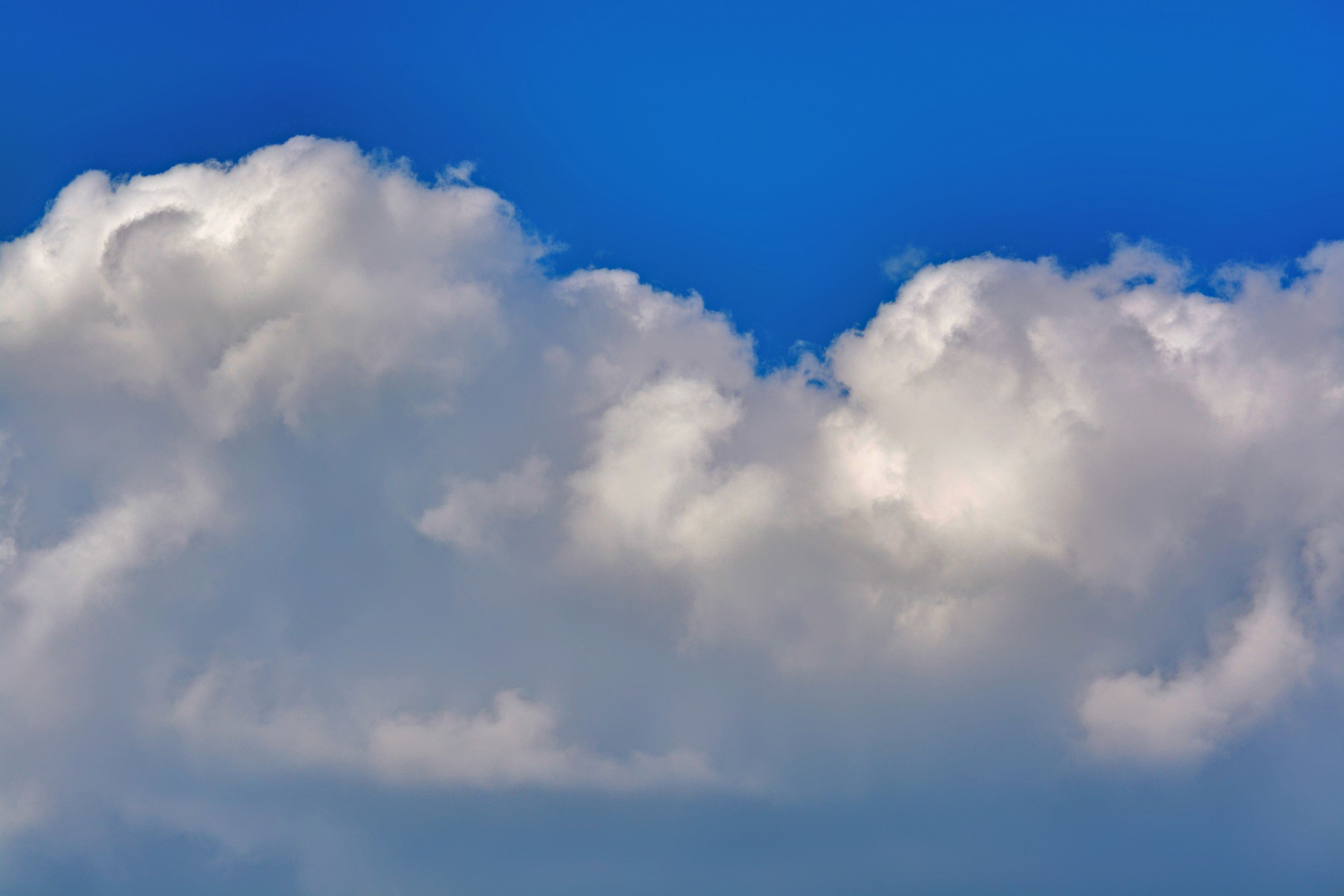 Billowing white cumulus clouds against a deep blue sky