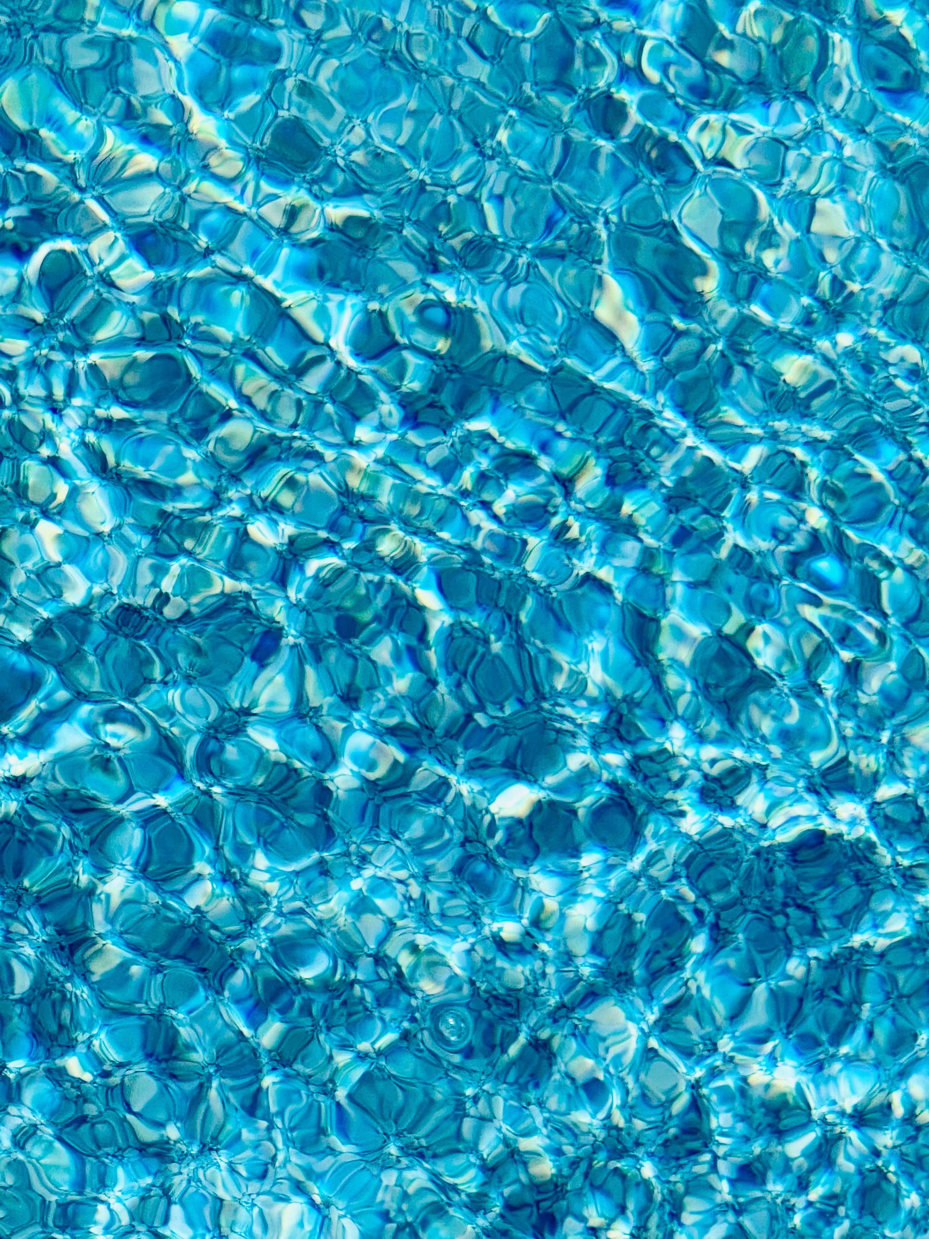 Turquoise pool water rippling in a cellular light pattern, sunlit and abstract