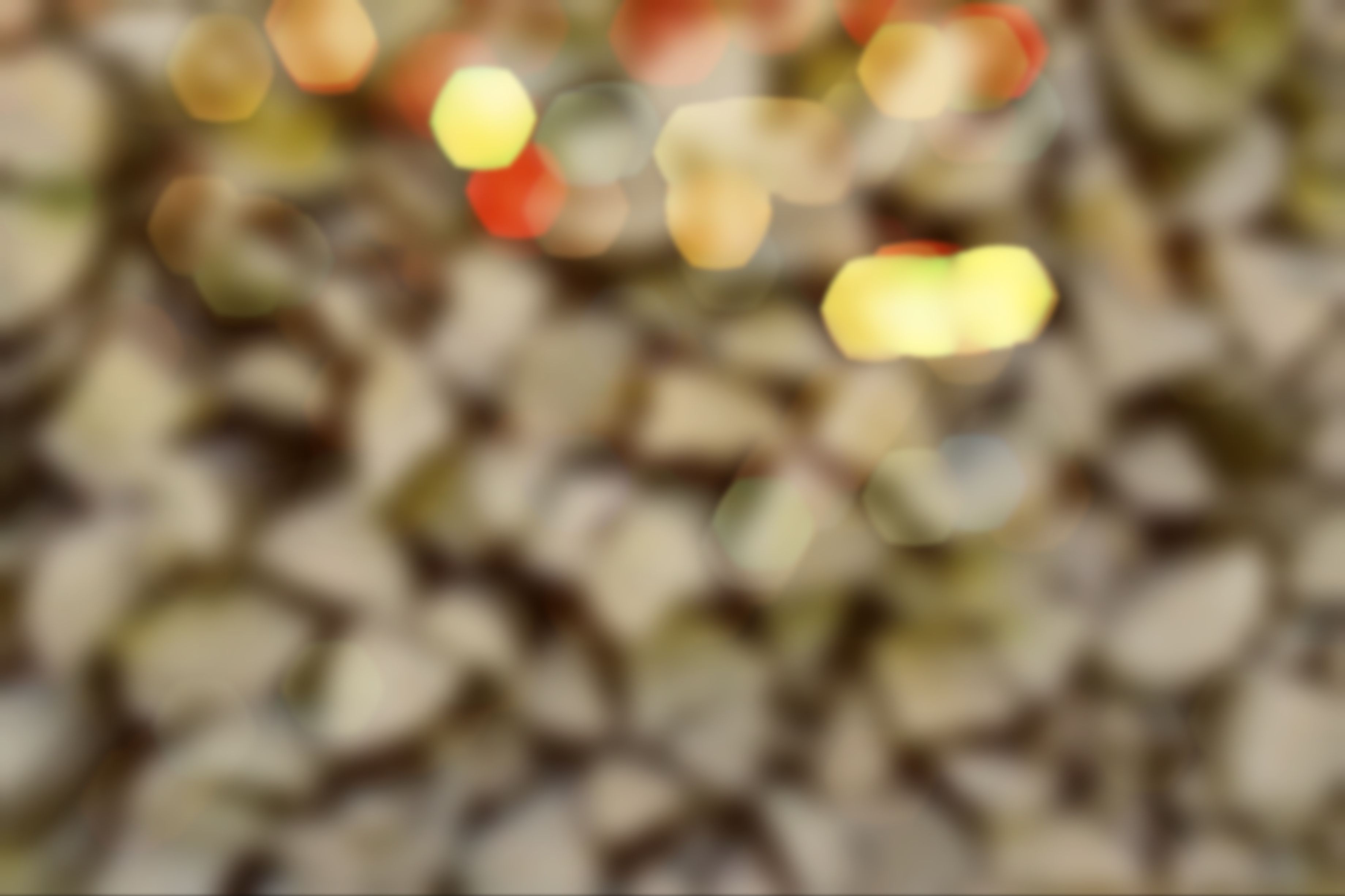 Abstract warm-toned bokeh blur with soft yellow, red, and gold light spots