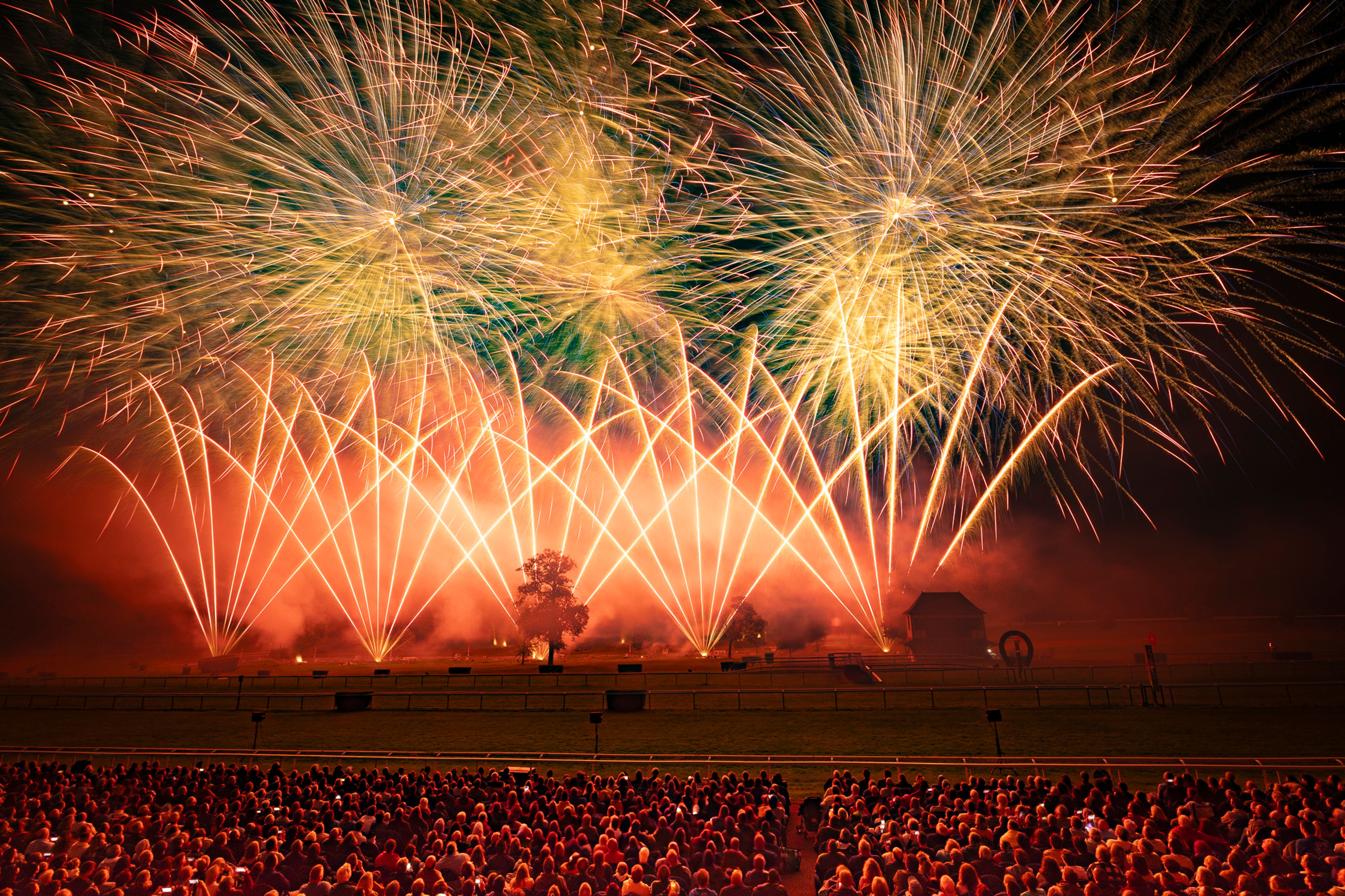A large crowd watches a fireworks display with bright yellow, orange, and red bursts lighting up the night sky over a park in Compiègne, France, during the Masters de Feu 2024 event on September 21.