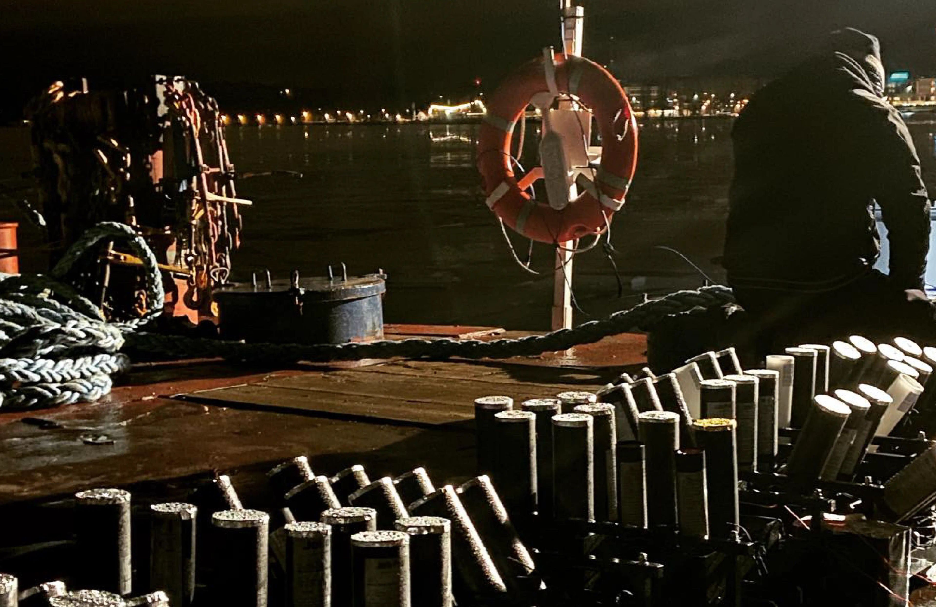 Firework launch tubes arranged on a boat deck at night.