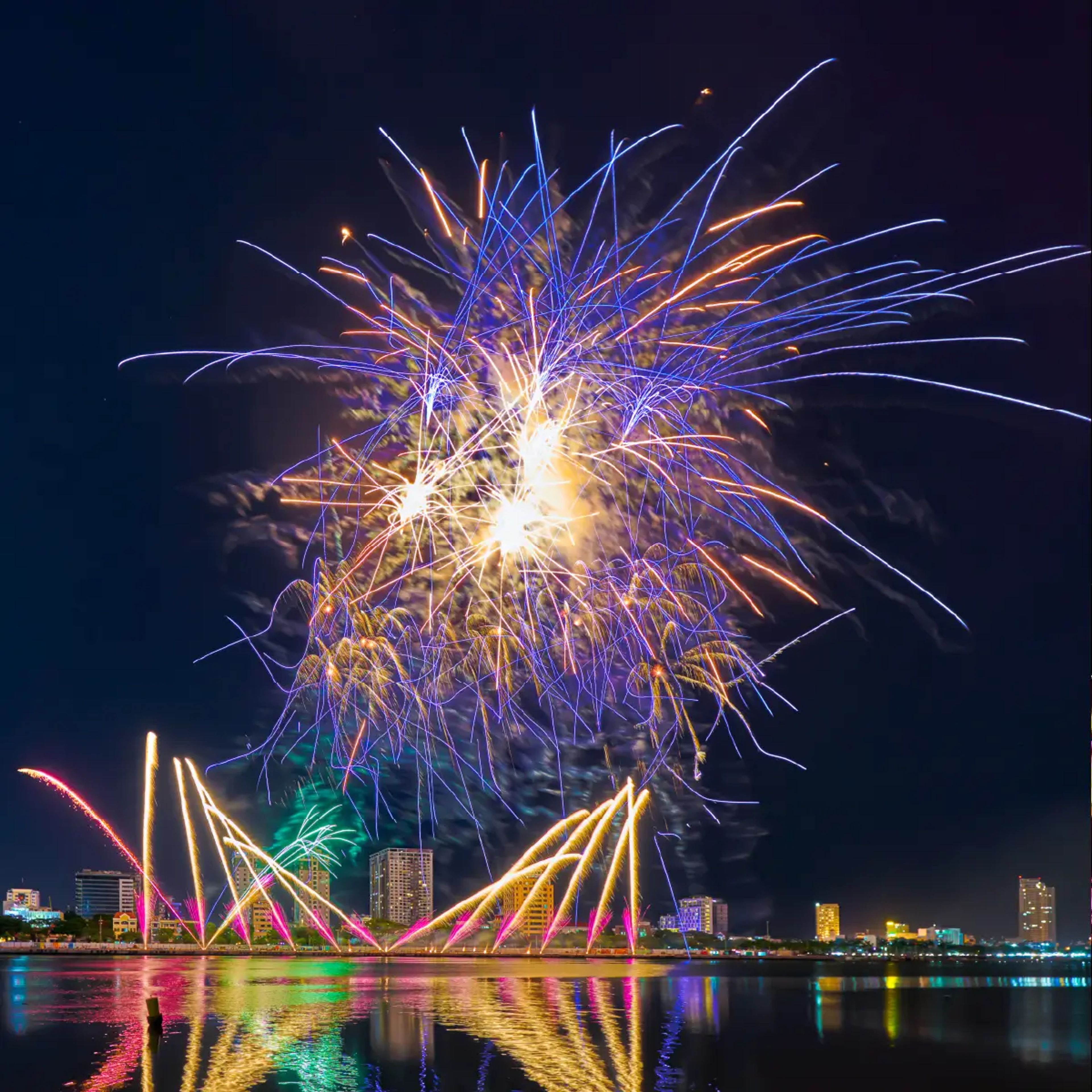 Blue, gold and pink fireworks reflected in the river at Da Nang.