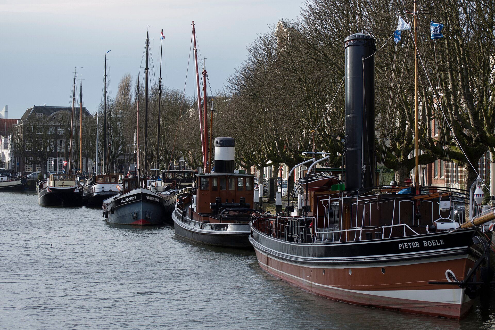 Historic ships moored along the Wolwevershaven quay in Dordrecht with merchant houses behind