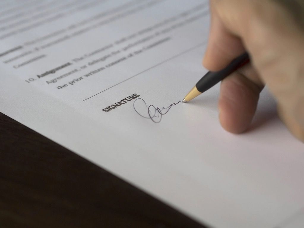 A person signing a Dutch rental contract at the signature line with a pen