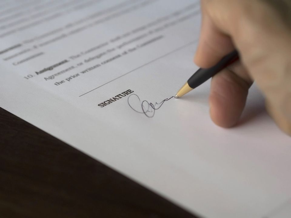 A person signing a Dutch rental contract at the signature line with a pen