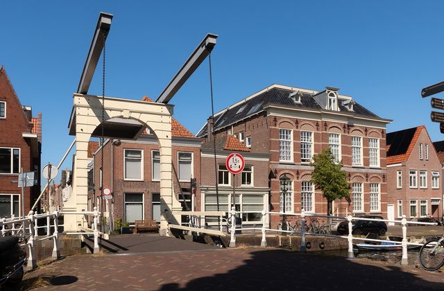 White drawbridge over the Verdronkenoord canal in Alkmaar with historic gabled houses and moored boats