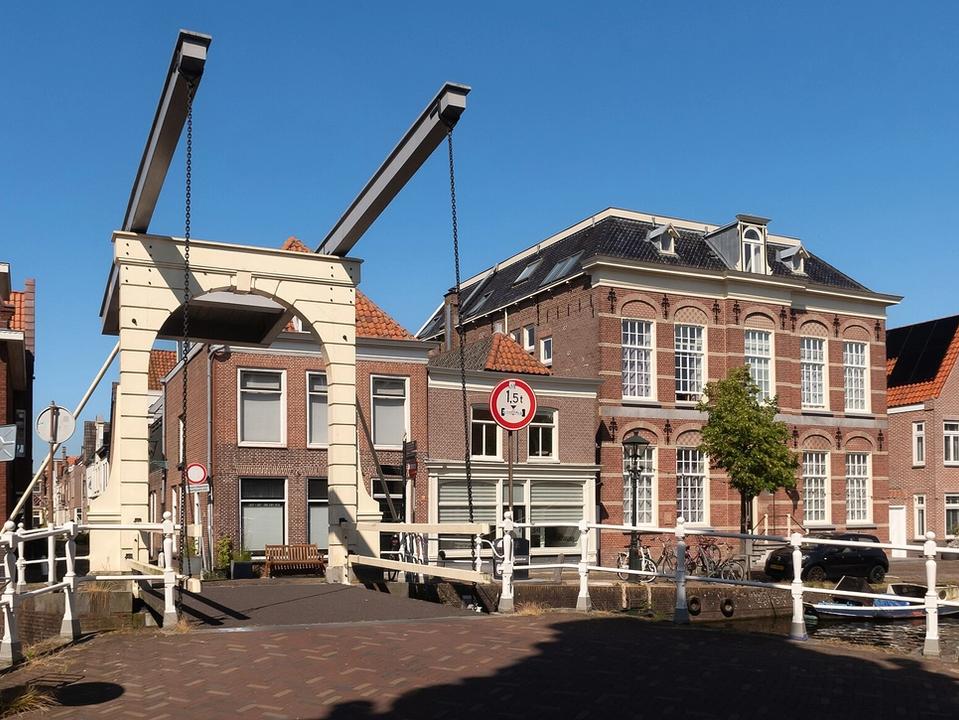 White drawbridge over the Verdronkenoord canal in Alkmaar with historic gabled houses and moored boats