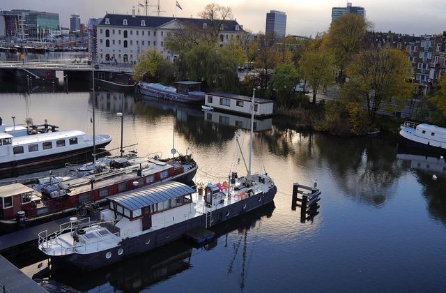 Houseboats and canal-side houses along an Amsterdam waterway at dusk