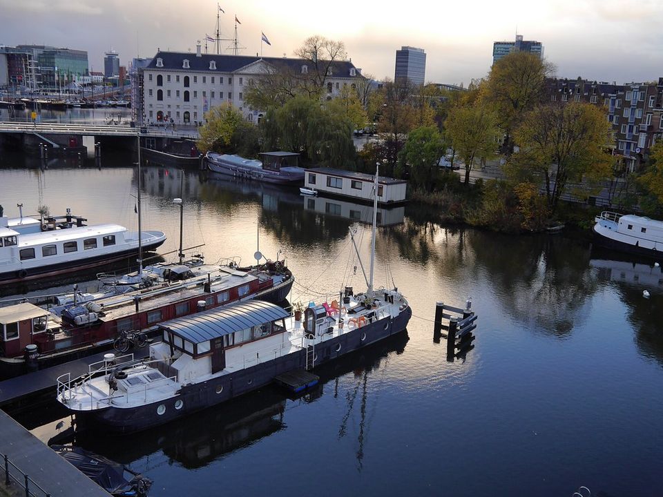 Houseboats and canal-side houses along an Amsterdam waterway at dusk