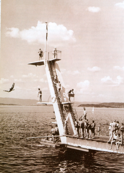 Historisk foto av stupetårnet med badeglade mennesker ventende på sin tur.