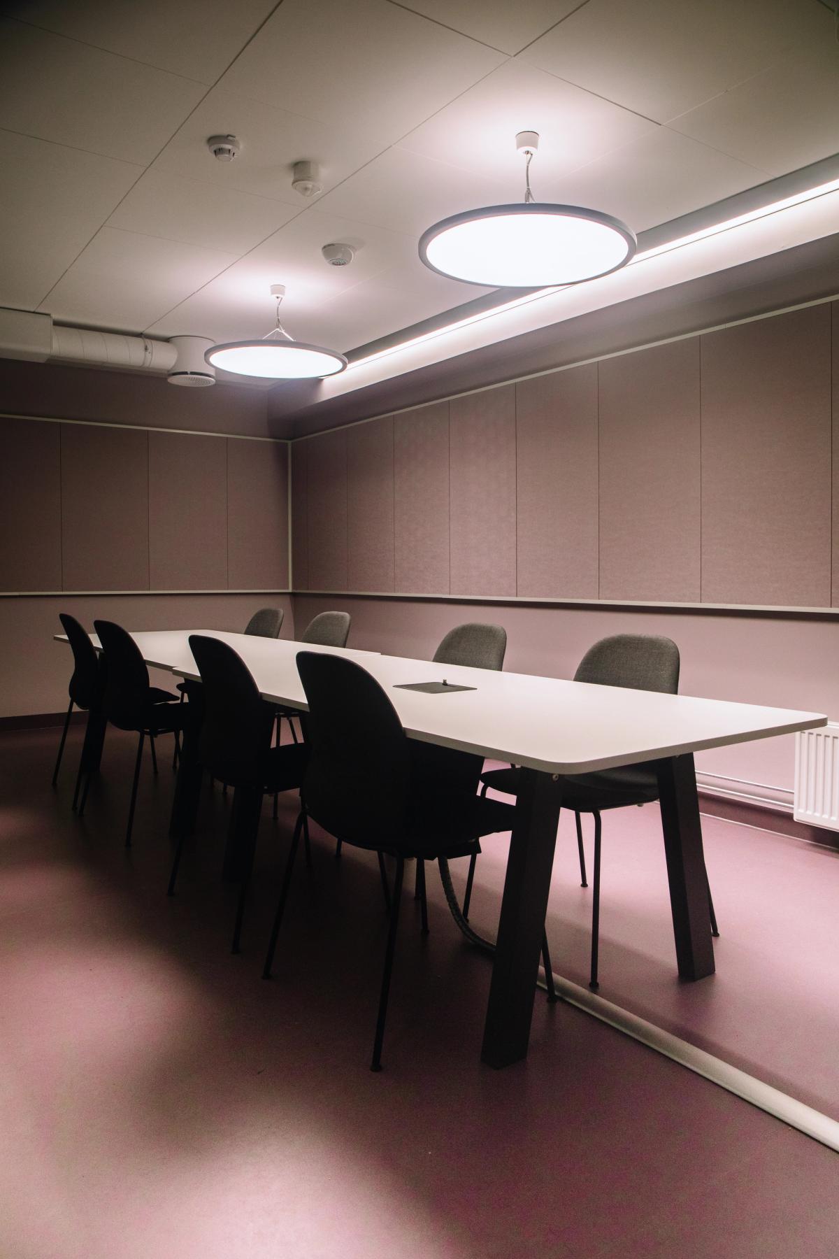 Foto av 10 personers møterom med lilla flater. Lilla gulv, lilla vegger og lilla veggabsorbenter. 