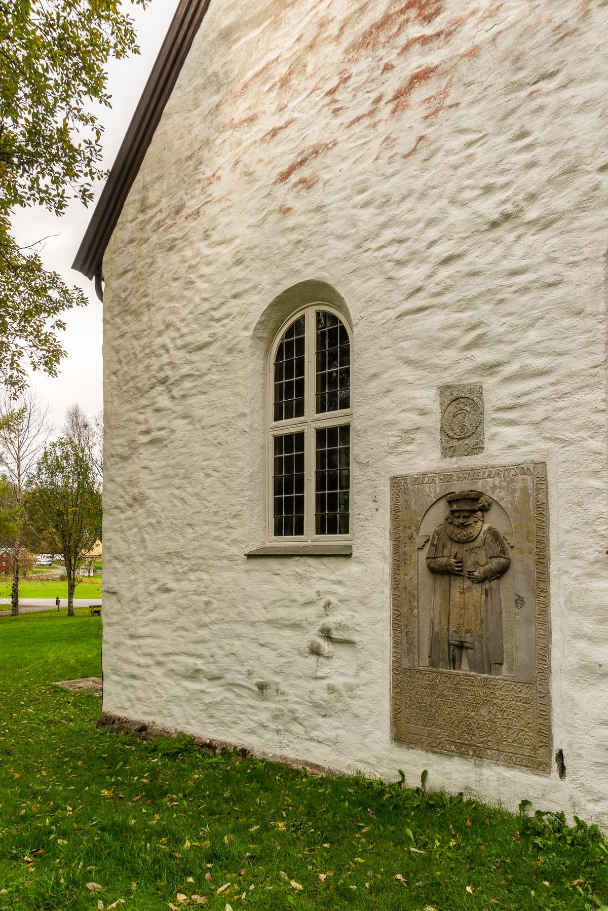 Foto av kirkens sidevegg med historisk motiv. 