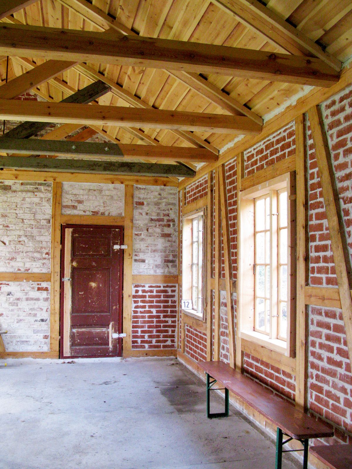 Foto av huset etter rehabilitering, og hvor tidligere grønn veggpanel er demontert og rød tegl er en del av interiøret. 