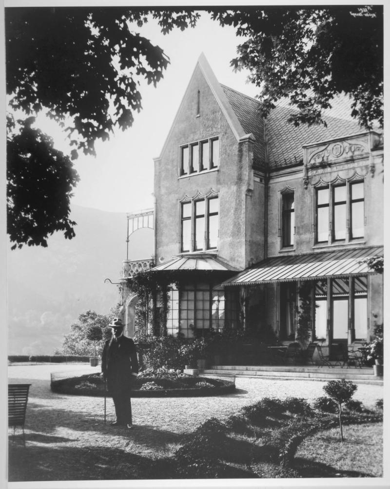 Historisk foto av Gamlehaugen. Fotografiet viser huset og hagen, samt en mann i flotte klær. WB Nilsen 1910. 