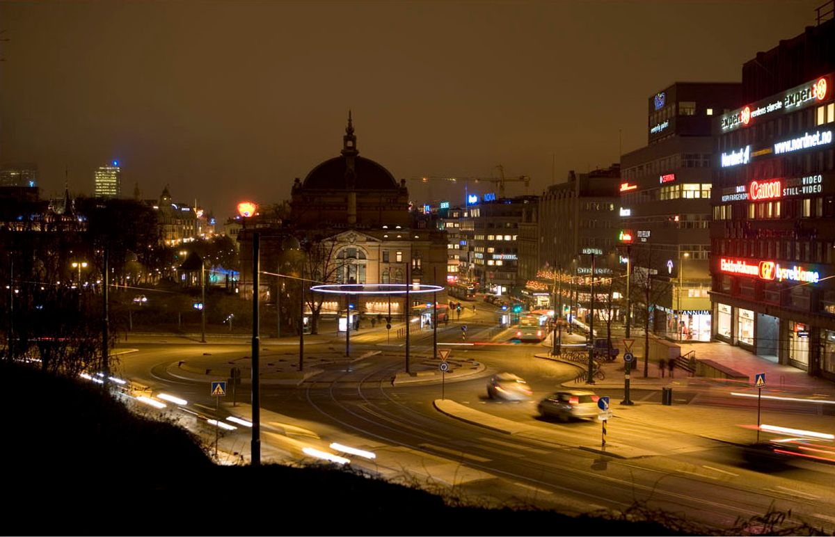 Kveldsfoto av rundkjøring, med biler og kveldslys.