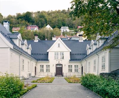 Foto av fasade etter restaurering. Hvitt bygg, hovedfløy og sidefløyene.