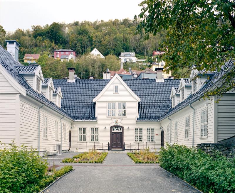 Foto av fasade etter restaurering. Hvitt bygg, hovedfløy og sidefløyene.