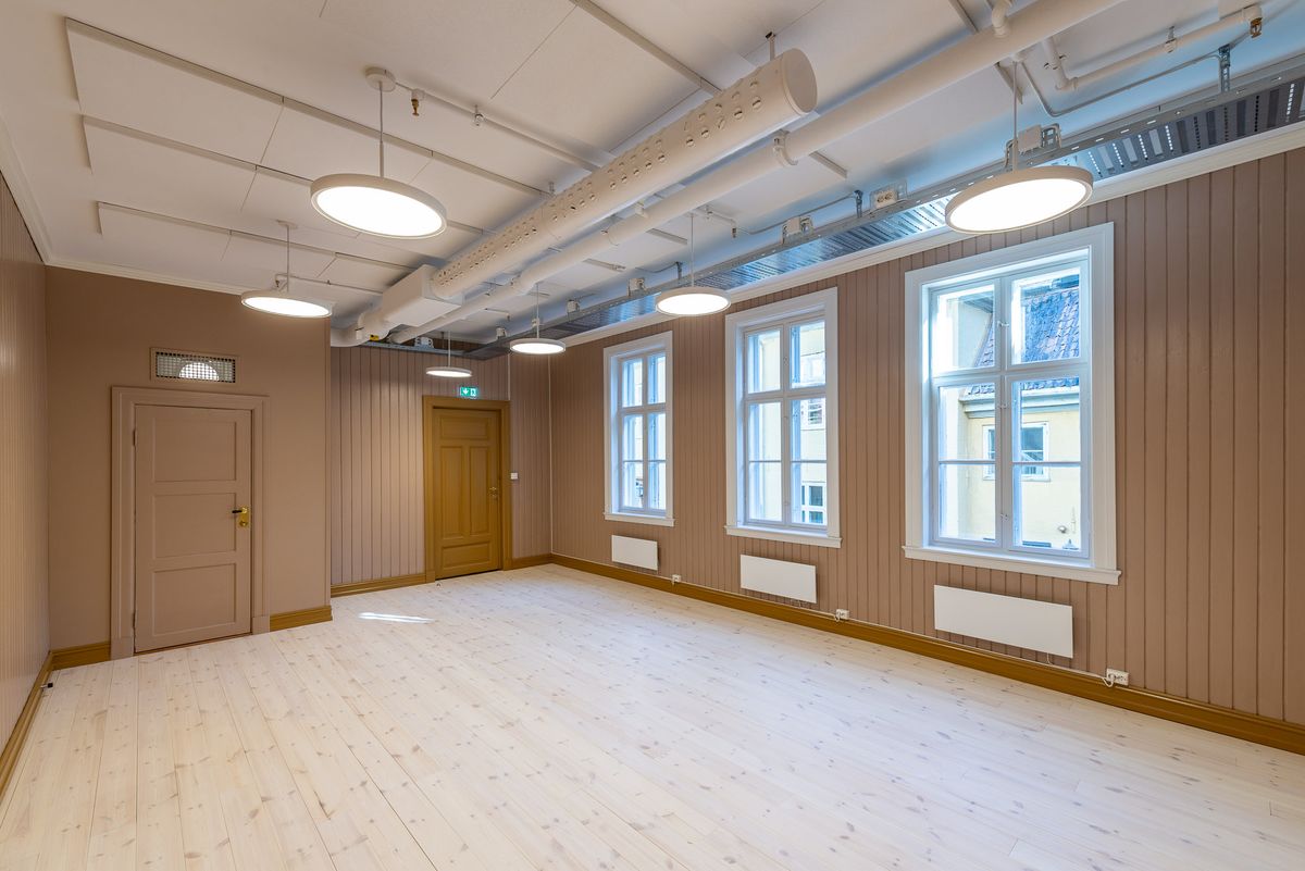 Fotografi av et stort rom i andre etasje med beige vegger og oker/brune detaljer. 