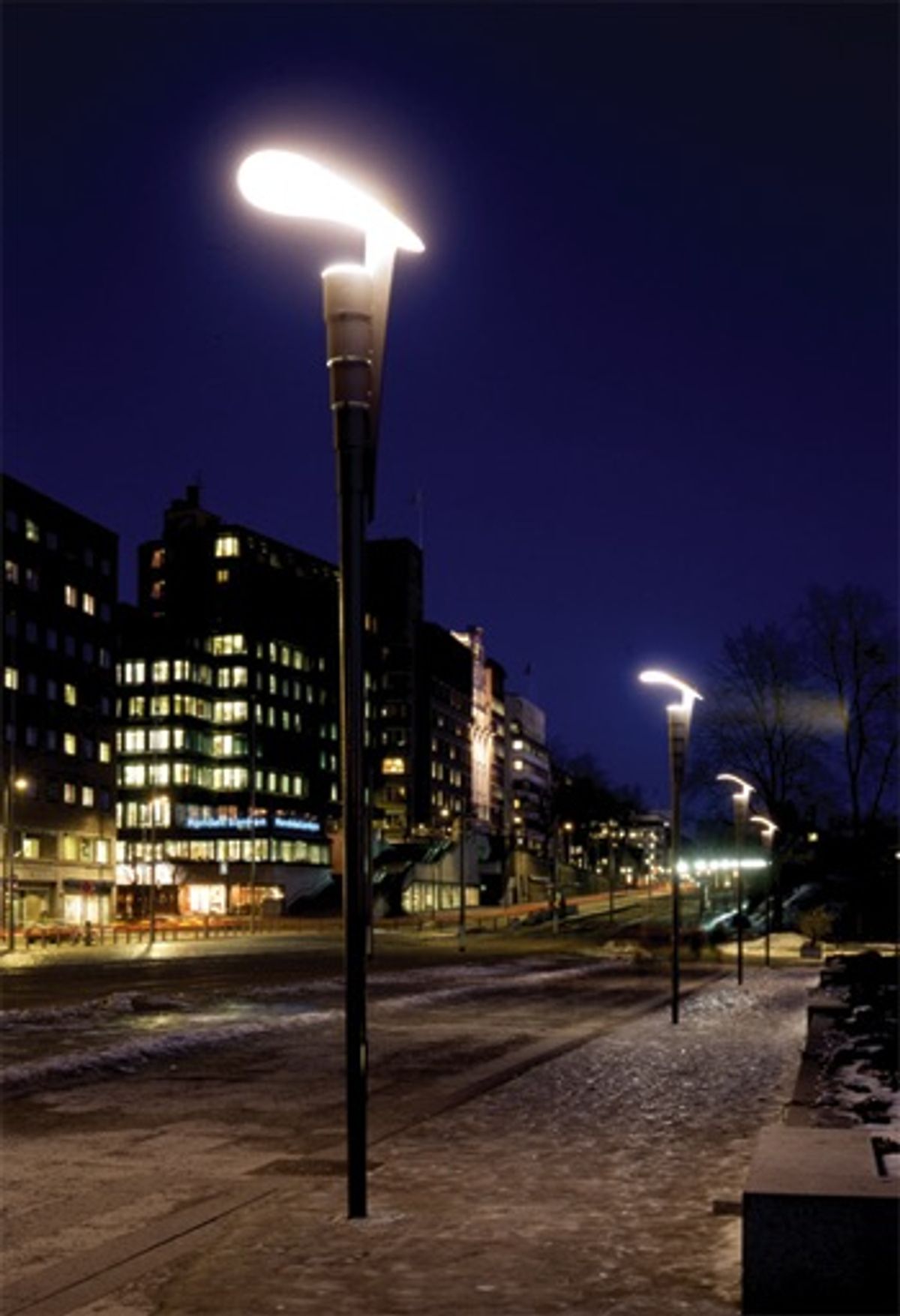 Kveldsfoto av Rådhusplassen med fokus på stolpelamper tatt fra gateplan.