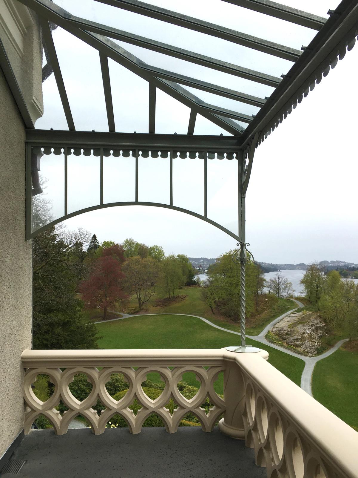 Foto tatt av terrassen i arbeidsprosessen. Viser et grønt landskap på en grå dag, og ferdig støpt rekkverk.