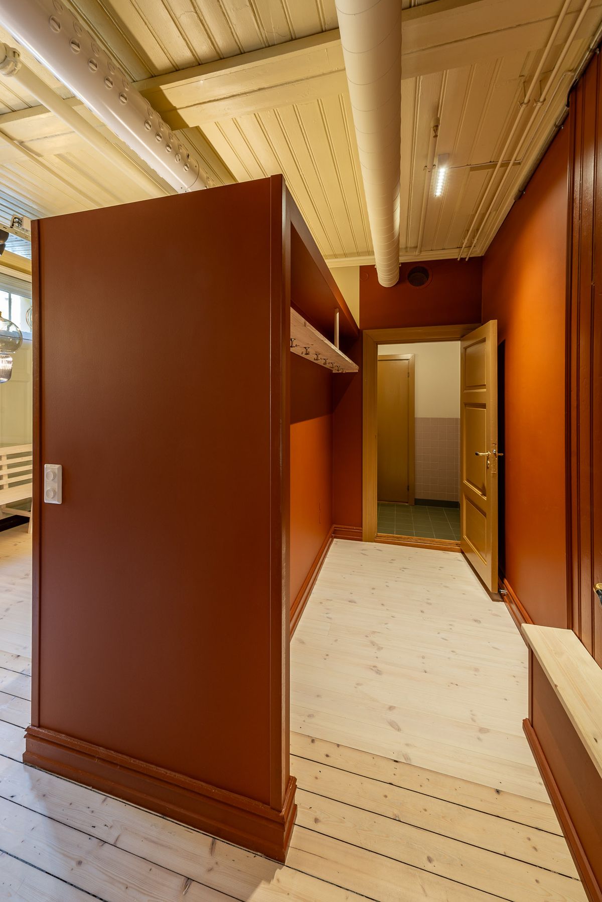 Fotografi av ny kjøkkeninnredning og korridor mot nye toaletter. Rød korridor. 